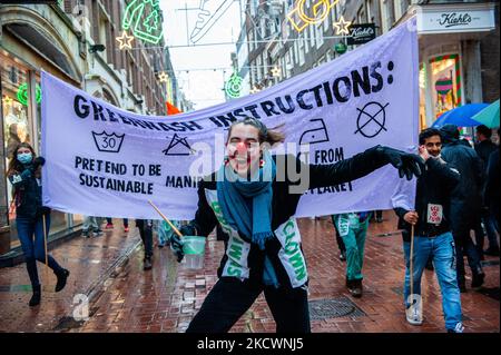 Un clown che rappresenta le pratiche di lavaggio del verde condotte dai marchi della moda, finge di dipingere con vernice verde, durante una sfilata di moda beffa Fast organizzata da XR, contro il Black Friday ad Amsterdam, il 27th novembre 2021. (Foto di Romy Arroyo Fernandez/NurPhoto) Foto Stock