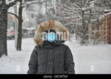 Donna che indossa una maschera facciale mentre cammina in una tempesta di neve durante la pandemia del nuovo coronavirus (COVID-19) a Toronto, Ontario, Canada il 28 novembre 2021. L'Ontario ha riferito il suo più alto numero di casi giornalieri COVID-19 in quasi sei mesi con 964 nuovi casi e un ulteriore decesso. Il Ministero della Salute dice che 498 dei casi di domenica sono tra le persone non vaccinate, 21 sono persone con una dose di vaccino COVID-19, 396 sono completamente vaccinate e 49 sono in persone con stato di vaccinazione sconosciuto. Ciò avviene in un momento in cui i paesi di tutto il mondo sono in forte allerta a causa dell'emergere del nuovo Omicron COVI, più contagioso Foto Stock