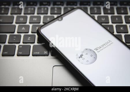 In questa illustrazione di foto un logo di Wikipedia visto visualizzato sullo schermo di uno smartphone con una parola chiave del computer in background ad Atene, Grecia, il 12 dicembre 2021. (Foto di Nikolas Kokovlis/NurPhoto) Foto Stock