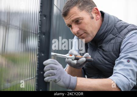 Lavoratore installazione di metallo saldata recinzione a maglia Foto Stock