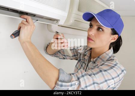 Giovane donna di pulizia condizionatore di aria in ambienti interni Foto Stock