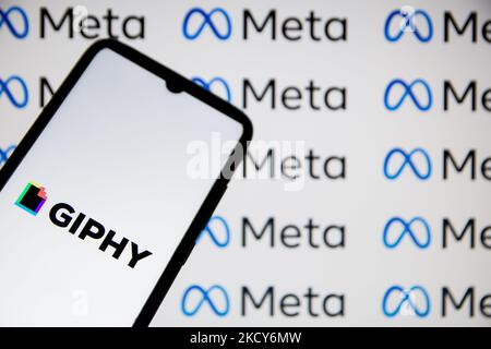 In questa foto, un logo Ghiphy visualizzato su uno smartphone con logo Meta sullo sfondo ad Atene, in Grecia, il 19 dicembre 2021. (Foto di Nikolas Kokovlis/NurPhoto) Foto Stock