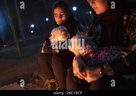 Due donne iraniane abbracciano i loro animali domestici mentre si siedono vicino al fuoco (non nella foto) in un parco vicino a un fiume Zayandeh Rud prosciugato lungo la città di Isfahan, 450 km (281 miglia) a sud di Teheran, la notte il 14 dicembre 2021. Un portavoce dell'Università di Scienze Mediche di Isfahan ha dichiarato: "Secondo l'ultima colorazione epidemica della malattia di Covid-19, la metropoli di Isfahan era in una condizione blu (a basso rischio), che è proporzionale alla diminuzione del numero di test coronarici positivi e di persone ospedalizzate." Secondo una notizia della Iranian Students News Agency (ISNA). (Foto di Morteza Niko Foto Stock