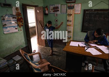 Il capomastro sta facendo un foglio del contrassegno e gli allievi giocano con la corda di salto ed entrano ripetutamente nella stanza dell'ufficio ad una scuola primaria rurale a Nabin Nagar, Bengala occidentale, India il 21/12/2021. (Foto di Soumyabrata Roy/NurPhoto) Foto Stock