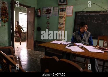 Il capomastro sta facendo un foglio del contrassegno e gli allievi giocano con la corda di salto ed entrano ripetutamente nella stanza dell'ufficio ad una scuola primaria rurale a Nabin Nagar, Bengala occidentale, India il 21/12/2021. (Foto di Soumyabrata Roy/NurPhoto) Foto Stock