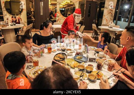 Un uomo vestito da Babbo Natale regala caramelle ai bambini al centro commerciale Lippo Plaza durante le festività natalizie del 26 dicembre 2021 a Medan, Indonesia. Natale è una festa nazionale in Indonesia, anche se solo circa il dieci per cento della popolazione è cristiana, dove rigorosi protocolli di salute tra i casi crescenti della variante COVID-19, Omicron. (Foto di Ivan Damanik/NurPhoto) Foto Stock