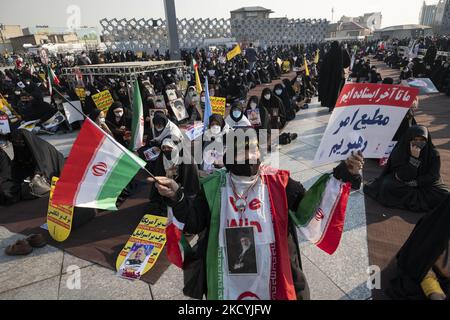 Una donna velata iraniana che indossa la bandiera iraniana e un ritratto del leader supremo iraniano Ayatollah Ali Khamenei partecipa a un raduno nella piazza Imam Hussein a Teheran sud-orientale il 30 dicembre 2021. I sostenitori del leader supremo iraniano Ayatollah Ali Khamenei partecipano a un raduno per celebrare l’anniversario delle manifestazioni anti-opposizione del 2009 dicembre a Teheran. (Foto di Morteza Nikoubazl/NurPhoto) Foto Stock