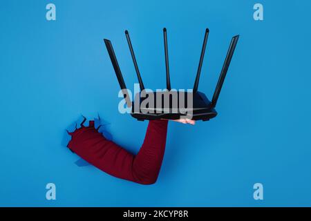 Nero router wifi a portata di mano su sfondo blu Foto Stock