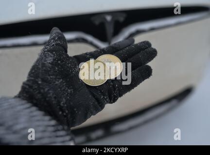 Immagine illustrativa di due bitcoins commemorativi visti di fronte all'auto Tesla durante il freddo venerdì 7 gennaio 2022 a Edmonton, Alberta, Canada. (Foto di Artur Widak/NurPhoto) Foto Stock