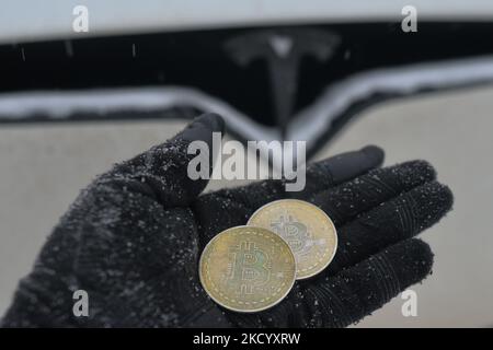 Immagine illustrativa di due bitcoins commemorativi visti di fronte all'auto Tesla durante il freddo venerdì 7 gennaio 2022 a Edmonton, Alberta, Canada. (Foto di Artur Widak/NurPhoto) Foto Stock