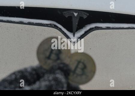 Immagine illustrativa di due bitcoins commemorativi visti di fronte all'auto Tesla durante il freddo venerdì 7 gennaio 2022 a Edmonton, Alberta, Canada. (Foto di Artur Widak/NurPhoto) Foto Stock