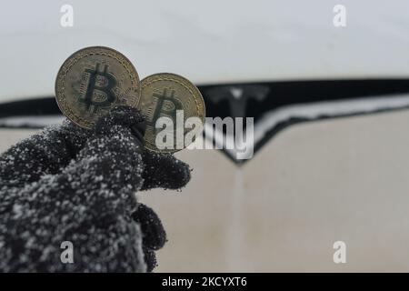 Immagine illustrativa di due bitcoins commemorativi visti di fronte all'auto Tesla durante il freddo venerdì 7 gennaio 2022 a Edmonton, Alberta, Canada. (Foto di Artur Widak/NurPhoto) Foto Stock