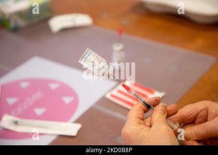 Primo piano alla siringa, al flaconcino e alle mani di una donna che prepara il booster shot. L'operatore sanitario pubblico GGD prepara i vaccini Moderna Spikevax mRNA Covid-19 prelevandoli dal flacone di vetro del flaconcino alle singole dosi nelle siringhe nell'area speciale del mega centro di vaccinazione di Eindhoven. I jab sono somministrati come dose di richiamo. Il richiamo della terza dose è disponibile per tutti i Paesi Bassi oltre al blocco mentre la nazione combatte le epidemie della nuova mutazione del coronavirus variante di omicron della pandemia. Eindhoven, Paesi Bassi il 7 gennaio 2022 (Foto di N Foto Stock