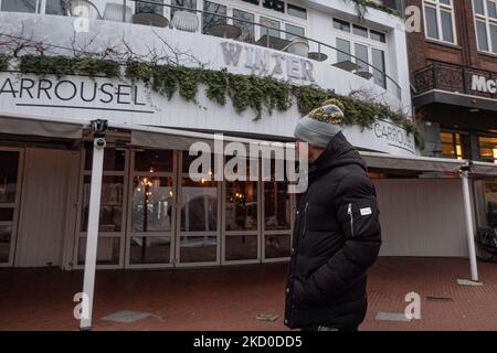 Un uomo passa davanti a un ristorante chiuso a Eindhoven durante il blocco. I Paesi Bassi sollevano in parte le misure di blocco dal 15 gennaio dopo la chiusura di 4 settimane, con tutti i negozi non essenziali che aprono con orario di lavoro limitato, università, parrucchieri e palestre, con capacità ridotta, ma caffè, bar e ristoranti resteranno sicuramente chiusi fino al 25 gennaio, un'azione che trova molti proprietari di negozio contro. Vita quotidiana a Eindhoven, mentre la gente cammina nel quartiere commerciale del centro o attendere in fila per ricevere i prodotti dai negozi tramite clic e raccogliere Foto Stock