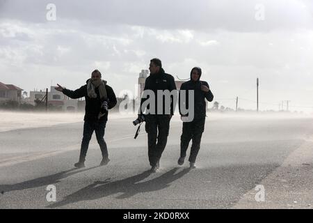 Fotoreporter palestinesi camminano durante il tempo tempestoso lungo una spiaggia sul Mar Mediterraneo nella città meridionale della striscia di Gaza, il 19 gennaio 2022. (Foto di Majdi Fathi/NurPhoto) Foto Stock