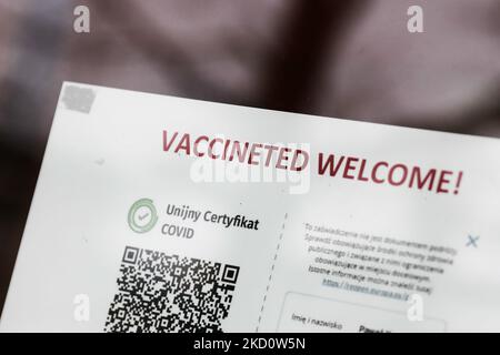 Il cartello "vaccinato di benvenuto" e il codice QR del certificato dell'Unione europea Covid sono riportati sulla porta d'ingresso di un ristorante a Cracovia, in Polonia, il 20 gennaio 2022. (Foto di Jakub Porzycki/NurPhoto) Foto Stock