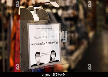 Il cartello "non entrare senza copertura facciale" e un liquido disinfettante sono visibili vicino all'ingresso di un negozio a Cracovia, in Polonia, il 20 gennaio 2022. (Foto di Jakub Porzycki/NurPhoto) Foto Stock