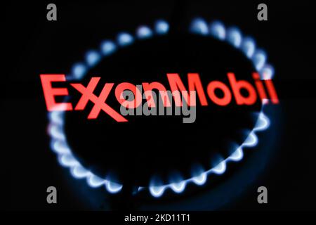 Le fiamme di un bruciatore a gas e il logo ExxonMobil visualizzato sullo schermo di un telefono sono visibili in questa foto di illustrazione a esposizione multipla scattata a Cracovia il 22 gennaio 2022. (Foto di Jakub Porzycki/NurPhoto) Foto Stock