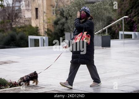 Una donna cammina con il suo cane al tacco dell'Acropoli indossando una maschera protetta ad Atene, in Grecia, il 23 gennaio 2022. (Foto di Nikolas Kokovlis/NurPhoto) Foto Stock