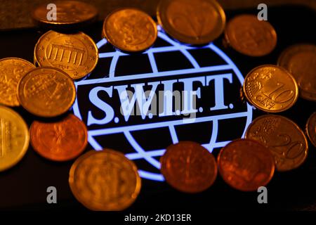 SWIFT (Society for Worldwide Interbank Financial Telecommunication) appare sullo schermo di un telefono e le monete sono viste in questa foto di illustrazione scattata a Cracovia, Polonia il 23 gennaio 2022. (Foto di Jakub Porzycki/NurPhoto) Foto Stock