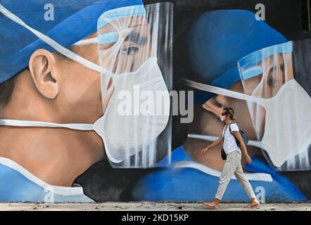 Una donna passa davanti a un murale di medici che indossano maschere dipinte nel centro di Merida dagli artisti messicani Mare - Noookye. Domenica 23 gennaio 2022, a Merida, Yucatan, Messico. (Foto di Artur Widak/NurPhoto) Foto Stock