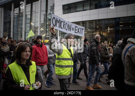 Un uomo ha un banner OMICRON=EXIT. Migliaia di persone protestano durante la dimostrazione europea per la democrazia contro le misure correlate a Covid come il pass sanitario COVID e le restrizioni. I disordini hanno cominciato a scoppiare e la polizia spara gas lacrimogeni e cannone d'acqua mentre la protesta si è trasformata in violenta. La gente partecipa a una manifestazione contro le misure sanitarie a Bruxelles come il COVID Health Pass, il codice QR, le maschere facciali e la vaccinazione obbligatoria, usando come slogan principale e sulle bandiere il termine liberte tradotto come libertà. Le autorità stimano che circa 50.000 persone provenienti da tutta Europa, compresa l'antiva Foto Stock