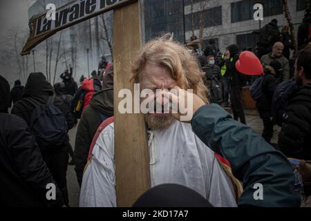 Un uomo sta tenendo una croce sta soffrendo bruciature dal gas lacrimale. Migliaia di persone protestano durante la dimostrazione europea per la democrazia contro le misure correlate a Covid come il pass sanitario COVID e le restrizioni. I disordini hanno cominciato a scoppiare e la polizia spara gas lacrimogeni e cannone d'acqua mentre la protesta si è trasformata in violenta. La gente partecipa a una manifestazione contro le misure sanitarie a Bruxelles come il COVID Health Pass, il codice QR, le maschere facciali e la vaccinazione obbligatoria, usando come slogan principale e sulle bandiere il termine liberte tradotto come libertà. Le autorità stimano che circa 50.000 persone provenienti da tutta la e Foto Stock