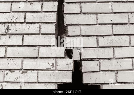 Muro esterno in mattoni con danni estremi crepe che trattengono dalla collisione del veicolo.Seppia foto in bianco e nero astratto foto di sfondo. Foto Stock