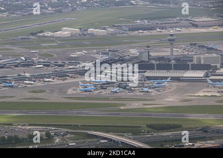 Il terminal dell'aeroporto con aerei KLM blu e altri alle porte. Vista aerea panoramica dell'aeroporto di Amsterdam, del terminal, della torre di controllo, degli aerei, delle piste, Taxi, parcheggio, aereo di prova fittizio per vigili del fuoco e la zona residenziale con case, strade e canali della capitale olandese Amsterdam come visto da un finestrino di un aereo dopo il decollo, con partenza dalla pista Ponderbaan dall'aeroporto Schiphol di Amsterdam. Amsterdam, Paesi Bassi il 4 maggio 2021 (Foto di Nicolas Economou/NurPhoto) Foto Stock