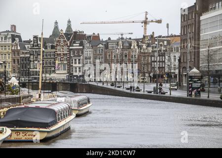 Le barche che solitamente fanno il giro turistico per i turisti sono viste ormeggiate nei canali di Amsterdam. Vita quotidiana durante il blocco alla quarta ondata della pandemia. Locali e alcuni turisti nelle tranquille strade di Amsterdam durante il blocco nella capitale olandese con negozi e negozi che appaiono con chiuso con la tapparella metallica giù, caffè, bar e ristoranti anche chiusi con tavoli e sedie delle terrazze chiuse. I Paesi Bassi sono stati la prima nazione europea a dichiarare il blocco completo per combattere la nuova variante di Omicron che si surge. Dopo un improvviso ordine governativo prima di Natale, il Foto Stock