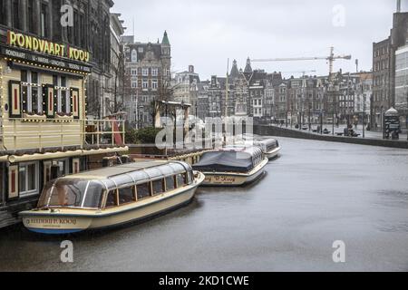 Le barche che solitamente fanno il giro turistico per i turisti sono viste ormeggiate nei canali di Amsterdam. Vita quotidiana durante il blocco alla quarta ondata della pandemia. Locali e alcuni turisti nelle tranquille strade di Amsterdam durante il blocco nella capitale olandese con negozi e negozi che appaiono con chiuso con la tapparella metallica giù, caffè, bar e ristoranti anche chiusi con tavoli e sedie delle terrazze chiuse. I Paesi Bassi sono stati la prima nazione europea a dichiarare il blocco completo per combattere la nuova variante di Omicron che si surge. Dopo un improvviso ordine governativo prima di Natale, il Foto Stock