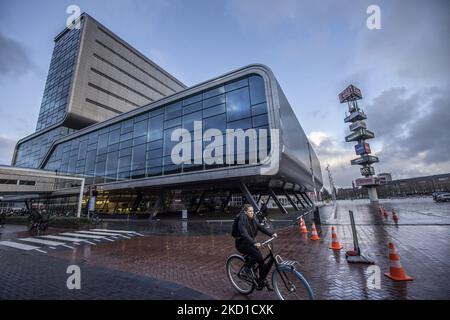 Una donna è in bicicletta presso i padiglioni espositivi della RAI. Vita quotidiana durante il blocco alla quarta ondata della pandemia. Locali e alcuni turisti nelle tranquille strade di Amsterdam durante il blocco nella capitale olandese con negozi e negozi che appaiono con chiuso con la tapparella metallica giù, caffè, bar e ristoranti anche chiusi con tavoli e sedie delle terrazze chiuse. I Paesi Bassi sono stati la prima nazione europea a dichiarare il blocco completo per combattere la nuova variante di Omicron che si surge. Dopo un improvviso ordine di governo prima di Natale, il paese ha chiuso tutte le none Foto Stock