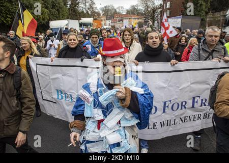 Una donna indossa un abito speciale fatto da maschere facciali mentre indossa una maschera medica sugli occhi e ha alcuni vaccini. Protesta contro il governo e le misure COVID nella capitale belga, Bruxelles. I manifestanti hanno marciato attraverso la città dalla stazione ferroviaria settentrionale verso l'Atomium, un simbolo e punto di riferimento della città attraverso il quartiere di Laeken. Secondo i media locali solo 1600 persone si sono riunite questa domenica. La manifestazione ha richiesto la rimozione del governo belga a causa delle misure pandemiche di Covid, come la vaccinazione obbligatoria, il Covid Health Pass, Q Foto Stock
