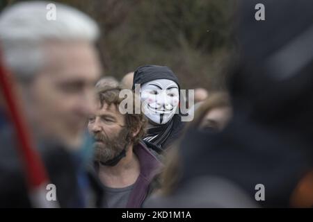 Un dimostratore indossa una maschera Vendetta - anonima. Protesta contro il governo e le misure COVID nella capitale belga, Bruxelles. I manifestanti hanno marciato attraverso la città dalla stazione ferroviaria settentrionale verso l'Atomium, un simbolo e punto di riferimento della città attraverso il quartiere di Laeken. Secondo i media locali solo 1600 persone si sono riunite questa domenica. La manifestazione ha richiesto la rimozione del governo belga a causa delle misure pandemiche di Covid, come la vaccinazione obbligatoria, il Covid Health Pass, il codice QR, maschere facciali, 5G cellulare ecc la polizia ha arrestato 3 proteste Foto Stock