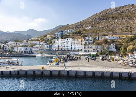 Scena del porto dell'isola con alcune piccole barche ormeggiate. Livadia, il porto e il villaggio principale dell'isola di Tilos con le case di architettura tradizionale imbiancate e la spiaggia con le acque cristalline del mare. Telos è una piccola isola greca mediterranea nel Mar Egeo, parte delle isole Dodecanesi, con una popolazione di 780 abitanti vicino alla costa turca. Alla fine del 2018 Tilos è diventata la prima isola del Mediterraneo a funzionare esclusivamente con energia eolica e solare, un'isola verde autosufficiente, un'iniziativa finanziata dall'UE per l'energia verde da fonti rinnovabili che proteggono il natu Foto Stock