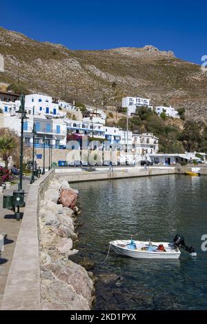 Scena del porto dell'isola con alcune piccole barche ormeggiate. Livadia, il porto e il villaggio principale dell'isola di Tilos con le case di architettura tradizionale imbiancate e la spiaggia con le acque cristalline del mare. Telos è una piccola isola greca mediterranea nel Mar Egeo, parte delle isole Dodecanesi, con una popolazione di 780 abitanti vicino alla costa turca. Alla fine del 2018 Tilos è diventata la prima isola del Mediterraneo a funzionare esclusivamente con energia eolica e solare, un'isola verde autosufficiente, un'iniziativa finanziata dall'UE per l'energia verde da fonti rinnovabili che proteggono il natu Foto Stock