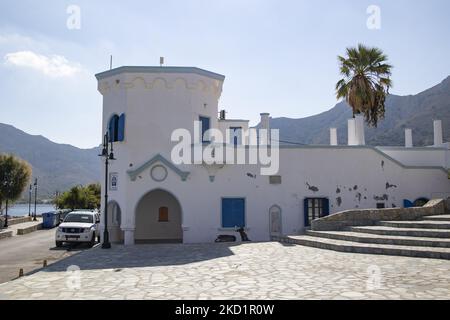 La bella stazione di polizia sul lungomare del villaggio. Livadia, il porto e il villaggio principale dell'isola di Tilos con le case di architettura tradizionale imbiancate e la spiaggia con le acque cristalline del mare. Telos è una piccola isola greca mediterranea nel Mar Egeo, parte delle isole Dodecanesi, con una popolazione di 780 abitanti vicino alla costa turca. Alla fine del 2018 Tilos è diventata la prima isola del Mediterraneo a funzionare esclusivamente con l'energia eolica e solare, un'isola verde autosufficiente, un'iniziativa finanziata dall'UE per l'energia verde da fonti rinnovabili che proteggono l'Europa Foto Stock