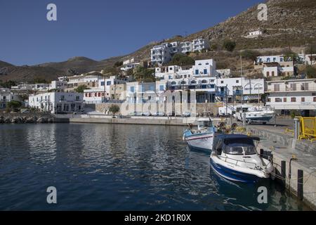 Scena del porto dell'isola con alcune piccole barche ormeggiate. Livadia, il porto e il villaggio principale dell'isola di Tilos con le case di architettura tradizionale imbiancate e la spiaggia con le acque cristalline del mare. Telos è una piccola isola greca mediterranea nel Mar Egeo, parte delle isole Dodecanesi, con una popolazione di 780 abitanti vicino alla costa turca. Alla fine del 2018 Tilos è diventata la prima isola del Mediterraneo a funzionare esclusivamente con energia eolica e solare, un'isola verde autosufficiente, un'iniziativa finanziata dall'UE per l'energia verde da fonti rinnovabili che proteggono il natu Foto Stock