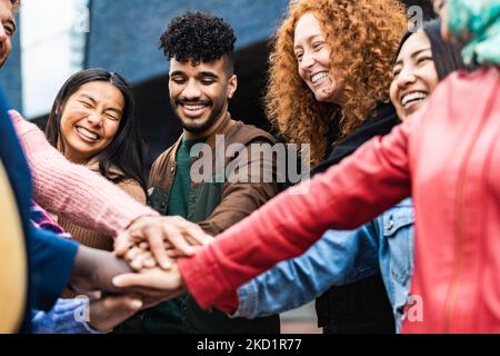 Amici multirazziali felici che hanno le mani di impilamento divertenti insieme all'aperto - gente dei giovani concetto di generazione millenaria Foto Stock