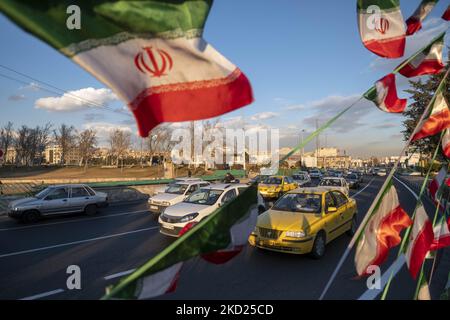 I veicoli viaggiano lungo un viale fino a piazza Azadi (libertà) nella parte occidentale di Teheran, decorata con bandiere iraniane per celebrare il 43rd° anniversario della vittoria della Rivoluzione islamica iraniana del 1979, in occasione dello scoppio della variante Omicron del COVID-19 in Iran, il 7 febbraio 2022. L'Iran ha nuovamente sperimentato l'aumento del numero di persone infettate da COVID-19 a causa della diffusione della variante di Omicron. (Foto di Morteza Nikoubazl/NurPhoto) Foto Stock