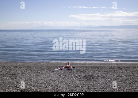 Giorno di sole e mare calmo alla spiaggia di Kohili, con ciottoli mentre una donna gode il sole, vicino al villaggio di Limni, una destinazione di viaggio, con il pendio bruciato e la foresta sullo sfondo. Dopo gli incendi scoppiati in Grecia, nel paese si è verificata un’enorme catastrofe ambientale. Nel punto specifico della riva, un'evacuazione con un traghetto ha avuto luogo in agosto, mentre l'incendio circondava l'area. Foreste, pini, oliveti, aziende, alberghi, campeggio, case, veicoli e animali sono stati bruciati. Il fuoco era finito dopo una notte di pioggia, mentre i precedenti vigili del fuoco greci, volun locale Foto Stock