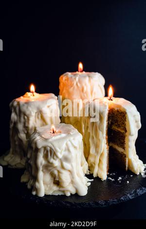Torte di candele fuse con fiamme reali: Torte fatte per assomigli alle candele accese su uno sfondo nero scuro Foto Stock
