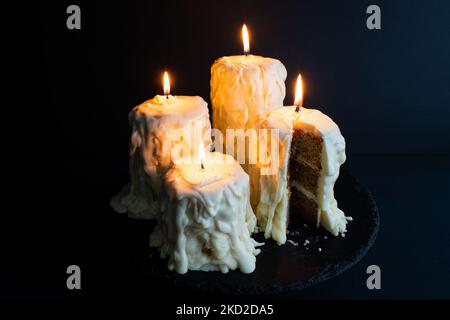 Torte di candele fuse con fiamme reali: Torte fatte per assomigli alle candele accese su uno sfondo nero scuro Foto Stock