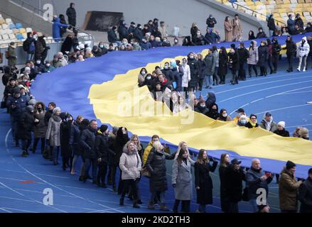 Gli ucraini portano un'enorme bandiera nazionale durante la celebrazione della Giornata dell'unità nello stadio Olimpiyskiy di Kiev, in Ucraina, il 16 febbraio 2022. "Ci viene detto che il 16 febbraio sarà il giorno dell'attacco. Lo faremo il giorno dell'unità. Il relativo decreto è già stato firmato. In questo giorno, alzeremo bandiere nazionali, metteremo nastri blu e gialli e mostreremo al mondo la nostra unità”, ha dichiarato il Presidente dell'Ucraina Volodymyr Zelenskiy. (Foto di Str/NurPhoto) Foto Stock