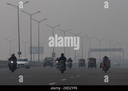 La gente viaggia lungo una strada in mezzo allo smog pesante al cancello dell'India a Nuova Delhi. La qualità dell'aria di Delhi rimane 'Evere', che rappresenta il 30 per cento dell'inquinamento del PM2,5 nella capitale, l'Indice di qualità dell'aria (AQI) a Noida (UP) è 529, 478 a Gurugram (Haryana) e 534 vicino a Dhirpur, tutti nella categoria 'severo'. Foto Stock