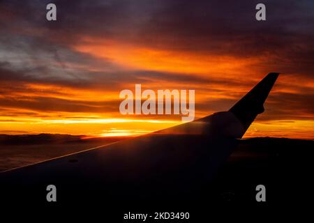 Brillante tramonto colorato dietro l'ala jet plane da copia cielo. Foto Stock