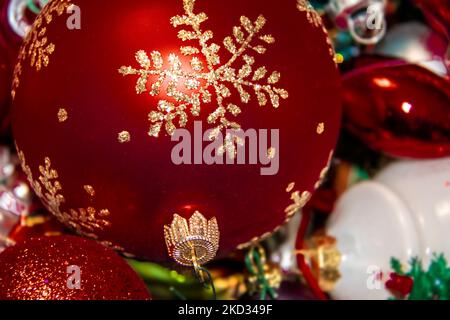 Sfondo di Natale - elegante ornamento glitttered albero rosso su pila di altri ornamenti bokeh. Foto Stock