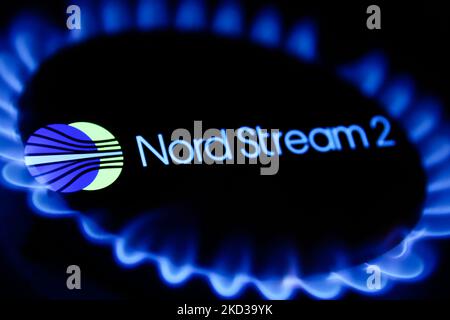 Le fiamme di un bruciatore a gas e il logo Nord Stream 2 visualizzato sullo schermo del telefono sono visibili in questa foto di illustrazione a esposizione multipla scattata a Cracovia il 22 febbraio 2022. (Foto di Jakub Porzycki/NurPhoto) Foto Stock