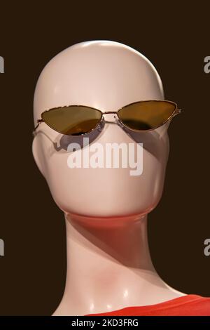 Testa manichino senza feature con occhiali da sole e una t-shirt arancione su sfondo nero Foto Stock