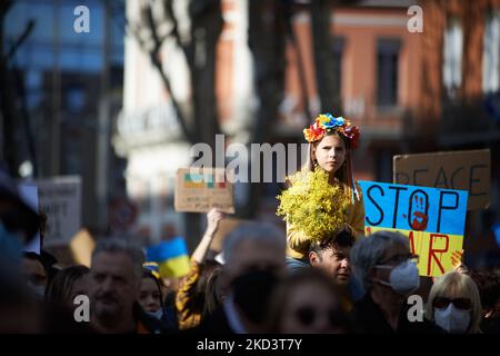 Una giovane ragazza siede sugli shuders del suo padre durante la protesta mentre tiene un mimosa bouquet. Migliaia di persone hanno marciato a Tolosa contro la guerra condotta dal presidente russo Vladimir Putin contro l'Ucraina a meno di una settimana dall'inizio dell'offensiva. Gli ucraini erano numerosi perché Tolosa ha un'importante comunità di ucraini. Tolosa è gemellare con Kiev. La Francia ha chiuso il proprio spazio aereo agli aeromobili russi e la Russia sta gradualmente interrando il sistema bancario SWIFT. Putin ha affermato di aver messo le sue forze di difesa nucleari in alto allarme. Tolosa. Francia. Febbraio 27th 2021. (Foto di Alain Pitti Foto Stock